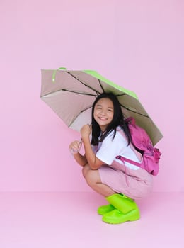Student young girl with green umbrella on pink background. photo