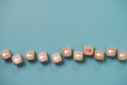 Disruption and technology transformation concept , Red arrow on wooden block cube move  in opposite direction from red arrow on blue background. photo