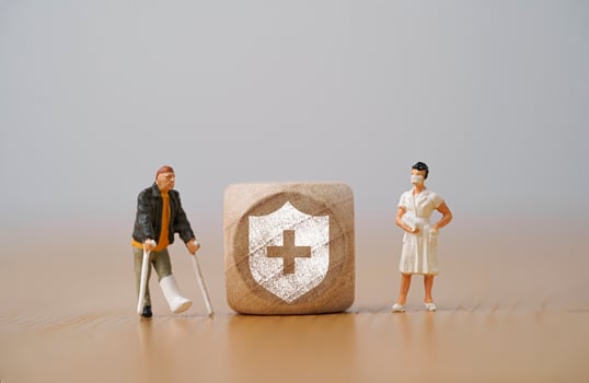 Miniature figure  man with a broken leg uses a crutch standing beside with nurse and insurance sign for healthcare assurance claim and medical concept. photo