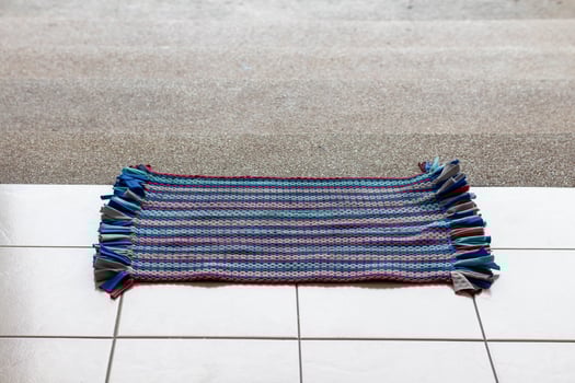The doormat is in front of the stairs before entering the building. photo
