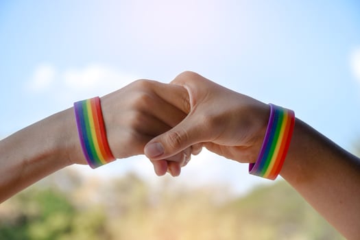 Rainbow rubber wristbands in wrists of asian boy couple with blurred background, concept for celebration of lgbt community in pride month or in June around the world. photo