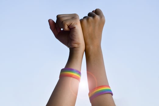Rainbow rubber wristbands in wrists of asian boy couple with blurred background, concept for celebration of lgbt community in pride month or in June around the world. photo