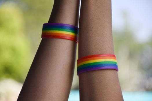 Rainbow rubber wristbands in wrists of asian boy couple with blurred background, concept for celebration of lgbt community in pride month or in June around the world. photo