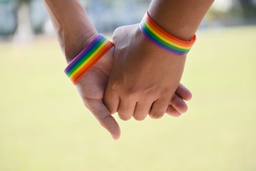 Rainbow rubber wristbands in wrists of asian boy couple with blurred background, concept for celebration of lgbt community in pride month or in June around the world. photo