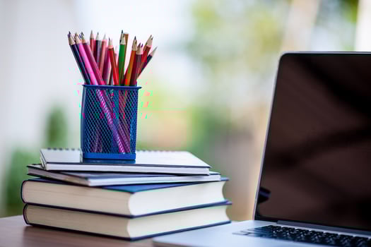 Pencils and books are placed beside the computer. photo