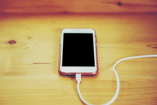 The phone is placed in a wooden table. And plug in the battery because the battery. Communication devices are important in everyday life in this era. photo