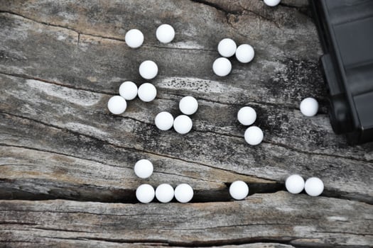 Closeup of white plastic bullets of airsoft gun or bb gun on wooden floor, soft and selective focus on white bullets. photo