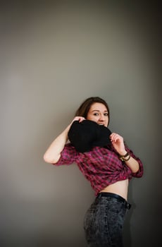 Portrait of brunette girl with cap wearing casual clothes background gray wall. photo