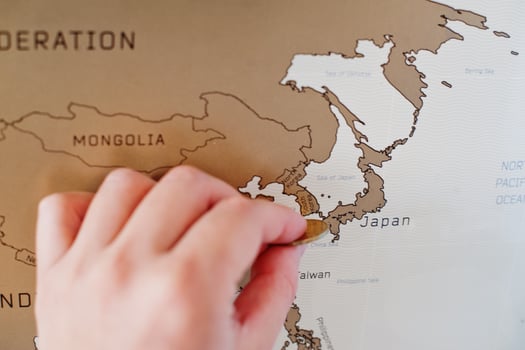 Scratch travel map of the world. Hand of man erase Japan with coin. photo