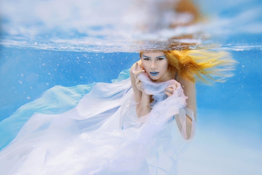 Underwater fashion portrait of beautiful blonde young woman in blue dress photo