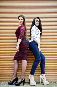 Two young teenages girl posed against orange shutter. Plump girl vs thin. photo