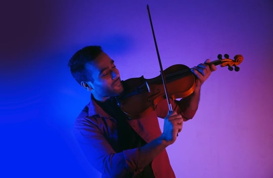 Man playing violin on studio low light neon lights photo