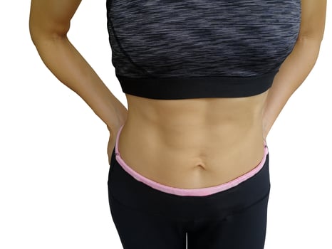 40 year old housewife with exercise and health care. A girl in a sports bra and exercise pants. A young woman exercising shows a six pack and body muscles at Fit Firm. photo