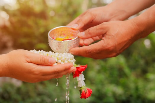 Young man's hands pour water and flowers on elder hand holding jasmine garland for Songkran festival photo