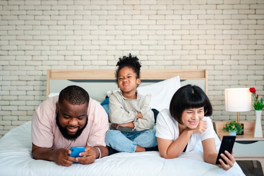 African American girls are not satisfied and sad, sitting in the middle between father and mother. Parents Are using the smartphone and abandoned children. Children need their parents attention. photo