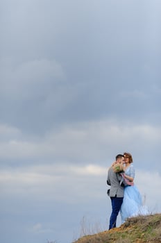 Wedding photo session of a couple on the seashore. Blue wedding dress on the bride.