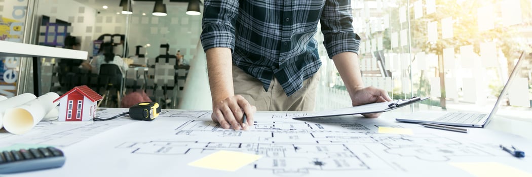 Interior designer or architect reviewing blueprints and holding pencil drawing on desk at home office. photo