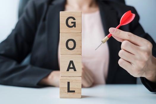 Hand holding red dart over Goal block. target, aim, objective, leadership, Business and marketing concept photo