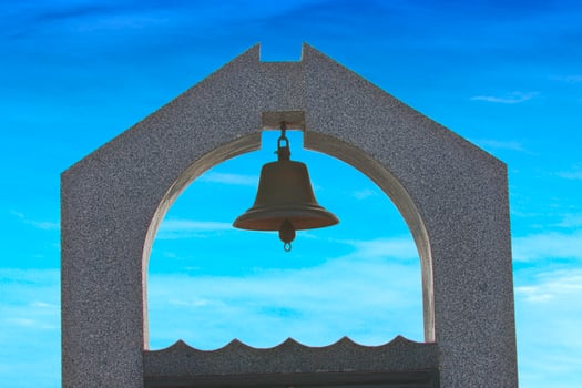 The bell at front with  the blue sky with the clear horizon on the background. photo