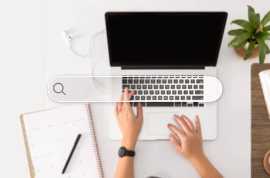 Search Button, Person Working on Laptop in the Background photo