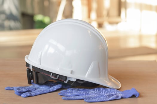 White safety helmet and blue gloves on the wooden floor. photo