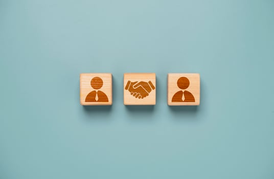 Drawing of hand shaking which print screen on wooden cube block  in front of human icon for business deal and agreement concept. photo