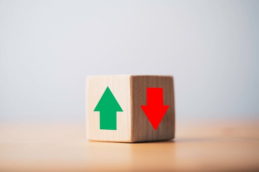 Focus of green up arrow in bright side and red down arrow in dark side which print screen on wooden cube block for economic and business profit growth concept. photo