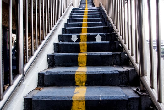 Yellow line and direction arrow painted on Concrete Stair of Overpass photo