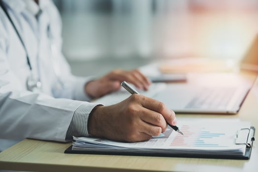 Doctor working with chart paper and laptop computer looking graph. Male doctor work at office hospital. Health hospital concept photo