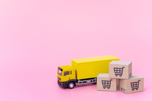 Logistics, and delivery service - Cargo truck and paper cartons or parcel with a shopping cart logo on Pink background. Shopping service on The online web and offers home delivery. photo