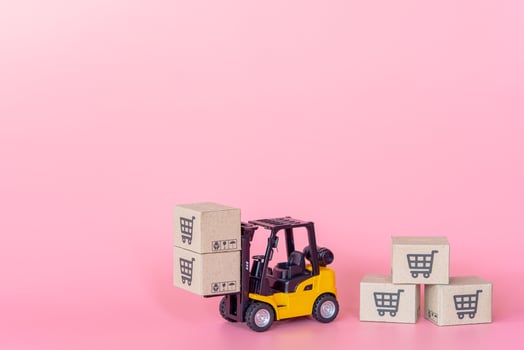 Logistics, and delivery service - Forklift model and paper cartons or parcel with a shopping cart logo on Pink background. Shopping service on The online web and offers home delivery. photo