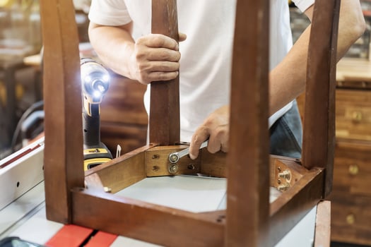 carpenter repair chair using Wrench at workshop, furniture restoration woodworking concept. selective focus photo