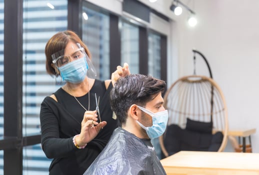 Young man getting haircut by hairdresser, Barber using scissors and comb, New normal concept photo