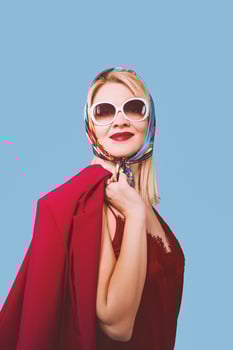 stylish smiling cheerful fancy blonde woman with make up in neckerchief and sunglasses on blue background photo