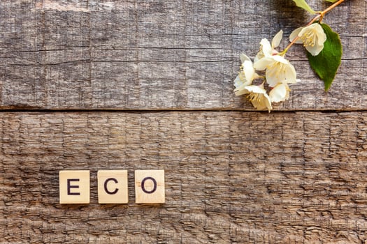 Inscription ECO letters word and jasmine flower on old rustic wooden background photo