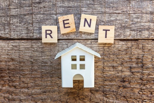 Miniature toy model house with inscription RENT letters word on wooden background photo