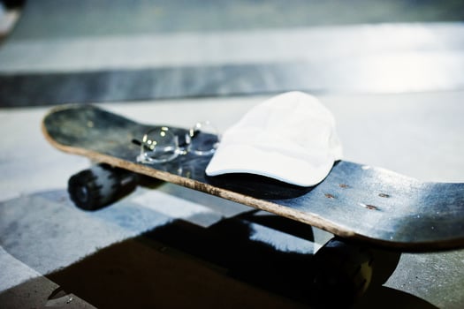 Skateboard with glasses and cap on skate park at evening. photo
