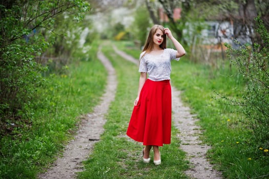 Portrait of beautiful girl with red lips at spring blossom garden, wear on red dress and white blouse. photo