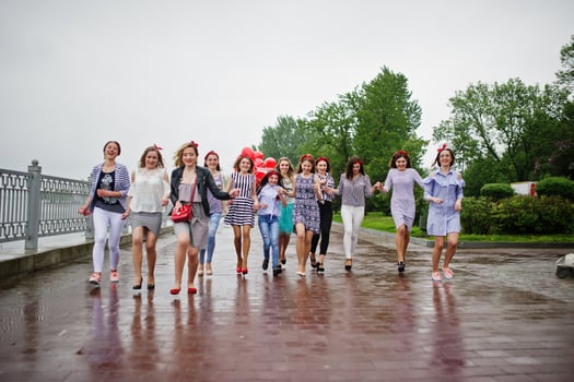 Eleven amazingly-looking braidsmaids with stunning bride posing with red heart-shaped balloons on the pavement against the lake in the background. photo