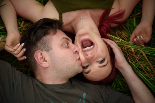 A man and a woman lie on their backs in a wheat field. A man kisses a woman on the cheek. The girl opened her mouth with delight. photo