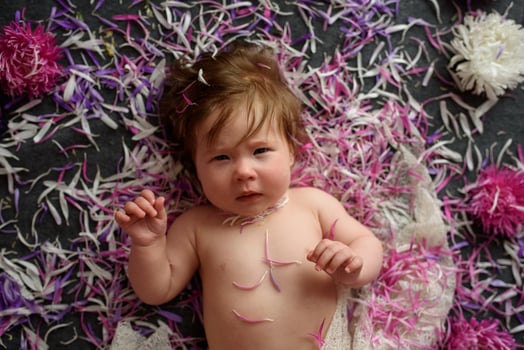 Portrait of a sweet little baby girl with a wreath of flowers on her head indoors photo