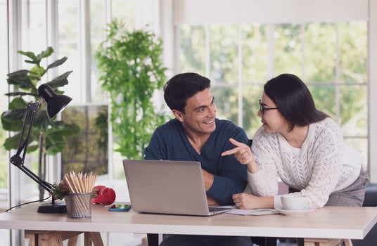Caucasian man and Asian woman mix race lovers working together via laptop notebook computer and discussing in living room with happy and intimate. New normal work at home office concept photo