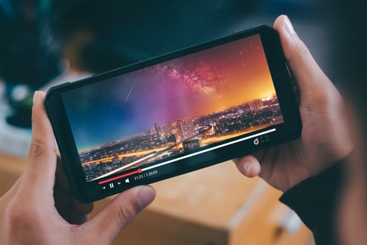 Online movie stream with smartphone. Young man  watching film on mobile phone with imaginary video player service. photo