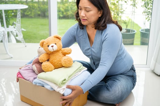 Holding clothing donation box with used clothes and doll at home to support help for poor people in the world. photo