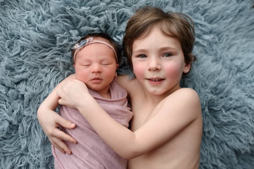 Older brother hugs his newborn sister. Shot from the top angle. photo