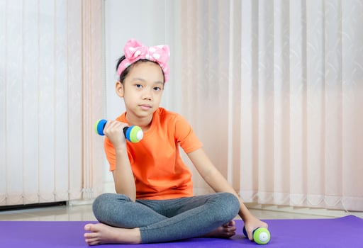 Happy girl doing exercises, kid lifting dumbbells at home, Kids playing concept photo