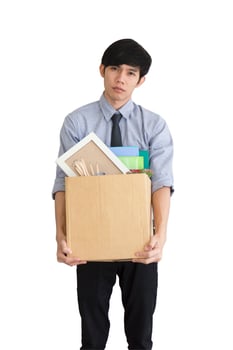 An Asian man stands sad on a white background after being fired, keeping his personal belongings in a carton box. photo