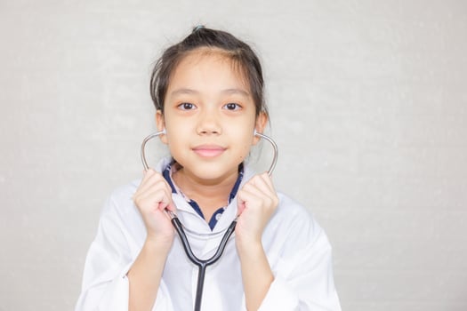 Dream careers concept, Portrait of Happy kid in doctor coat with stethoscope blurred background photo