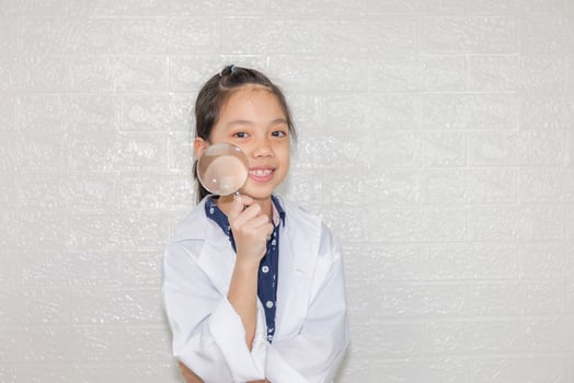 Dream careers concept, Portrait of Happy kid in science coat with magnifying glass on blurred background photo