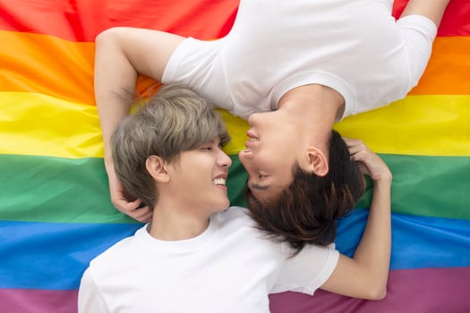 Male couples with Asian men sleep on a multicolored flag with an LGBT logo showing openly gay men accepting LGBT concepts. photo